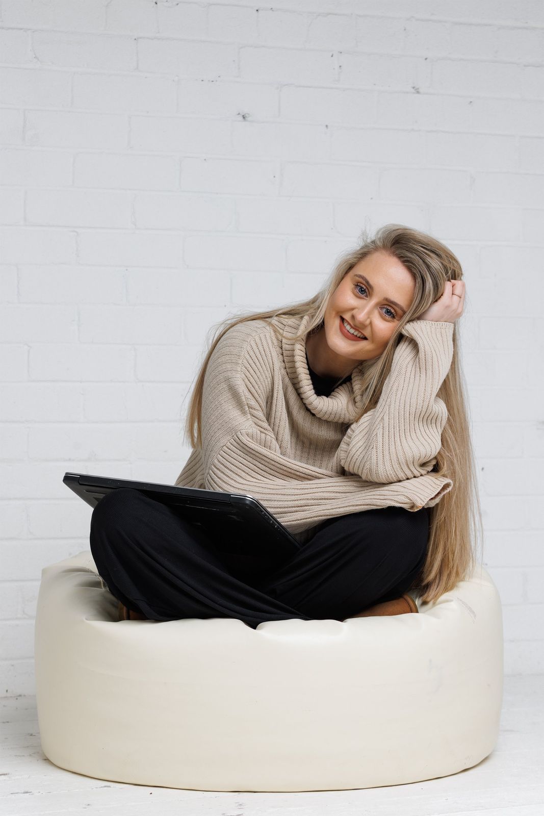 Victoria sitting cross-legged on a beanbag with a laptop