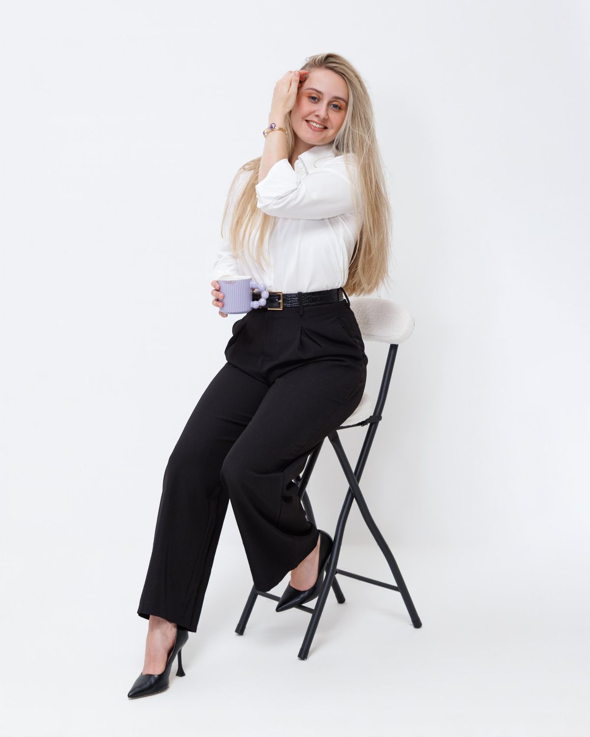 Victoria Connery sitting on a stool in the studio, holding a mug and smiling